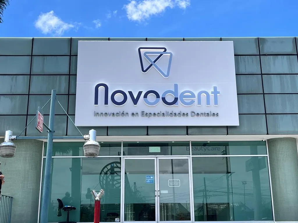 Fachada de la clínica en Plaza San Juan: el rótulo de Novodent, con el isotipo sobre el nombre, montado encima de la entrada de cristal.